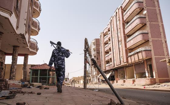 An armed police officer walks in the area of the Souk, in Omdurman, Sudan. Once famed for its gold market, every store had been picked clean by looters. MUST CREDIT: Eduardo Soteras for The Washington Post