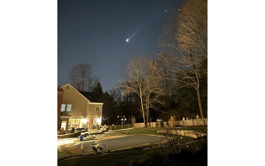 Multiple drones fly over the back yard of a suburban home at night.