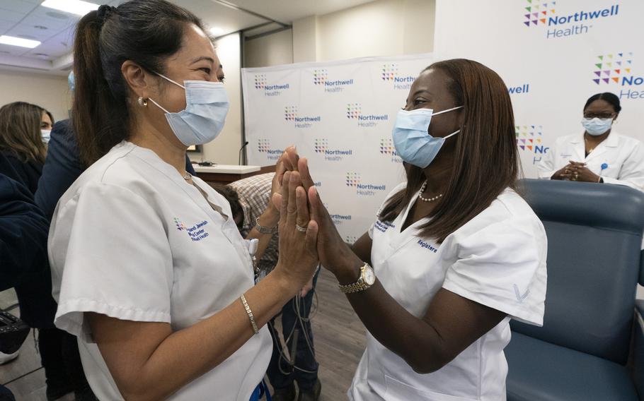 Nurse Annabelle Jimenez, left, congratulates nurse Sandra Lindsay after she is inoculated with the Pfizer-BioNTech COVID-19 vaccine, Monday, Dec. 14, 2020, at the Jewish Medical Center, in the Queens borough of New York. (AP Photo/Mark Lennihan, Pool)