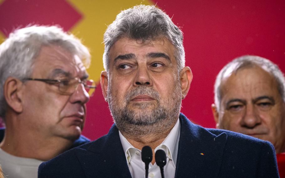 Marcel Ciolacu, the Romanian prime minister, stands in front of two microphones to speak after exit polls.