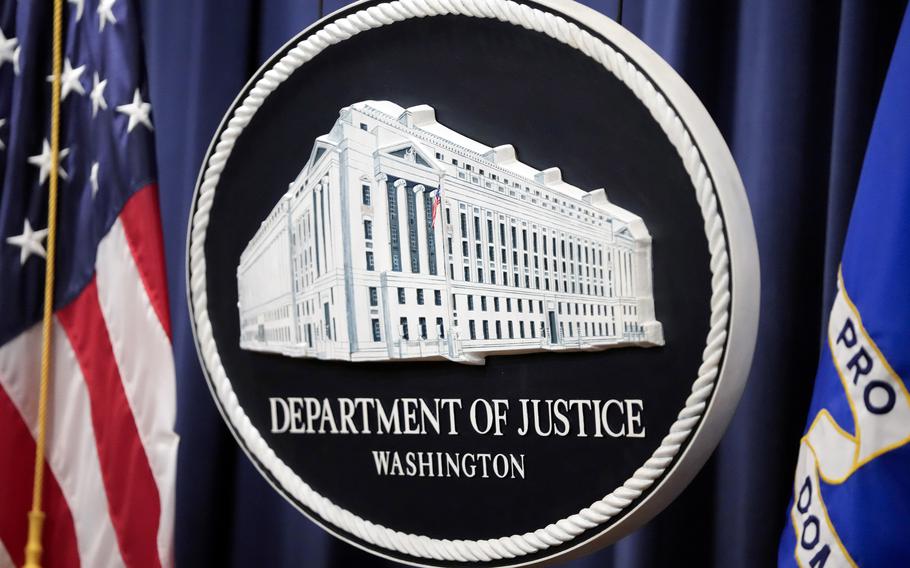 Close-up view of the emblem for the Department of Justice next to a U.S. flag.