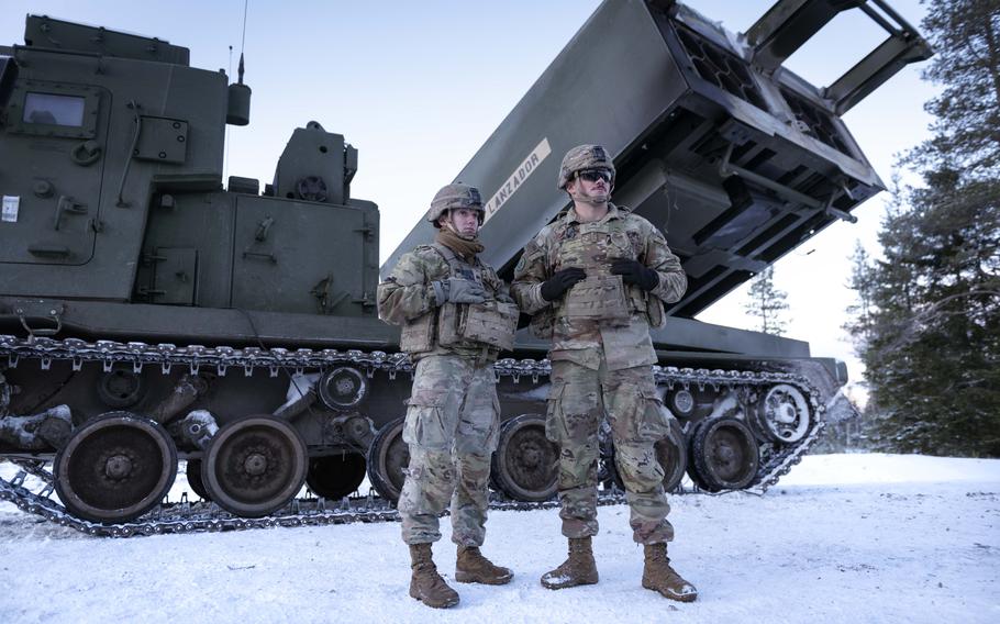 U.S. soldiers stand in front of an Army MLRS in snowy Finland.