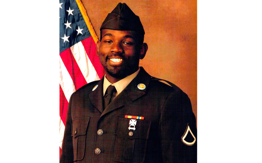 Posed photo of a soldier in uniform with the American flag behind his right shoulder.