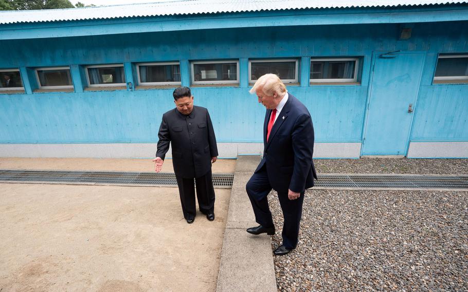 Kim Jong Un watches as Donald Trump goes up a step in front of the signature light blue buildings in the Joint Security Area of the DMZ.