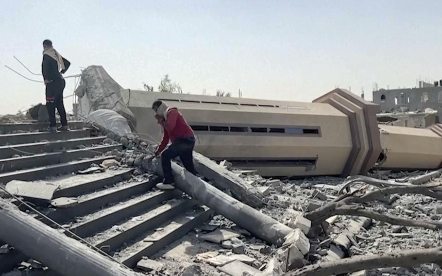 Two people walk by the remnants of a mosque destroyed by Israeli airstrikes in Khan Younis, Oct. 25, 2024.