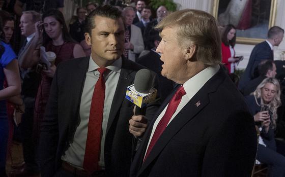 President Donald Trump speaks into a microphone while being interviewed by Pete Hegseth.