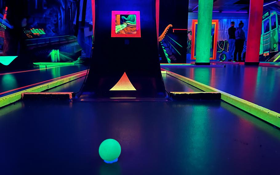 The mini golf hole with a neon green ball-shaped effect and a ramp.