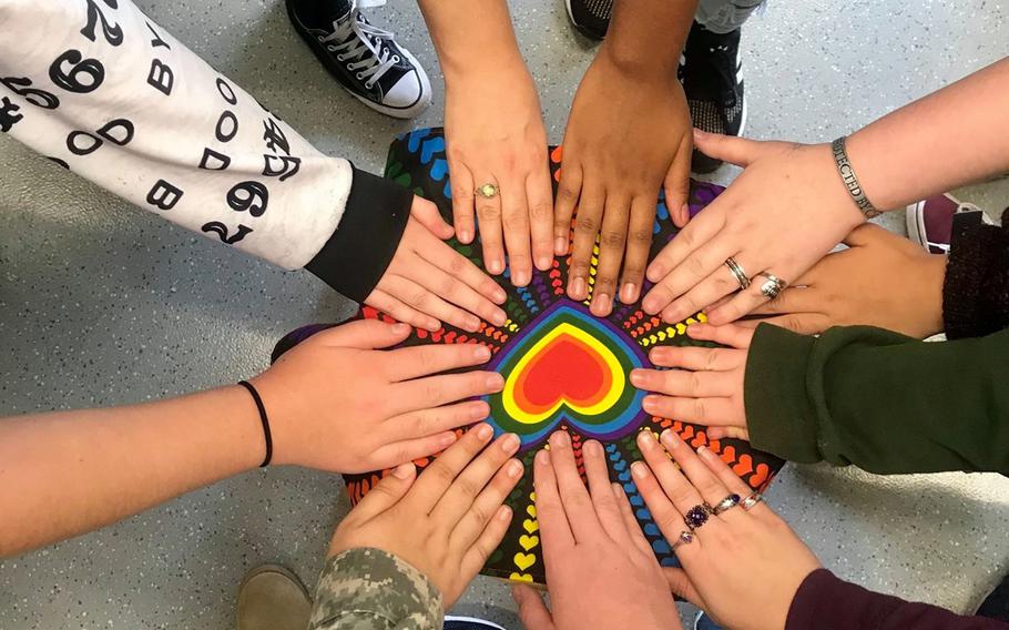 Hands reach in to touch an image of a red heart.