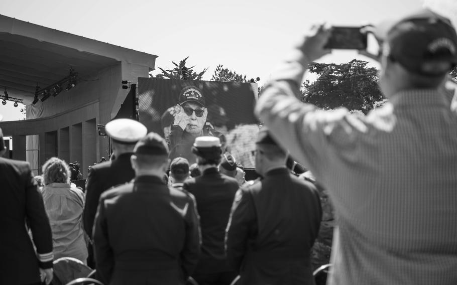 Army veteran Karl D. Kammer is projected onto a screen as he enters the D-Day ceremony grounds at Normandy American Cemetery, June 6, 2024. 
