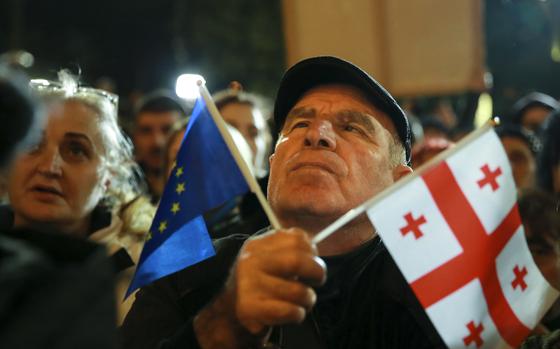 An opposition protester in Georgia holding both the E.U. and Georgian national flags, Oct. 28, 2024.