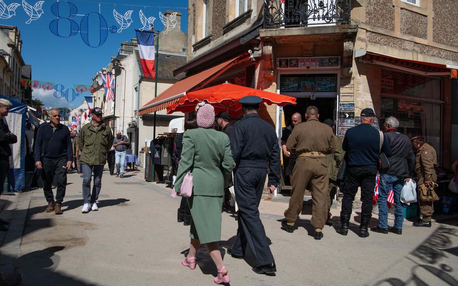 A couple dressed in 1940s attire walk through the streets of Arromanches-les-Bains, France, June 7, 2024.