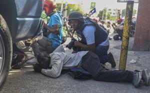 Journalists take cover from the exchange of gunfire between gangs and police in Port-au-Prince, Haiti, Monday, Nov. 11, 2024. (AP Photo/Odelyn Joseph)