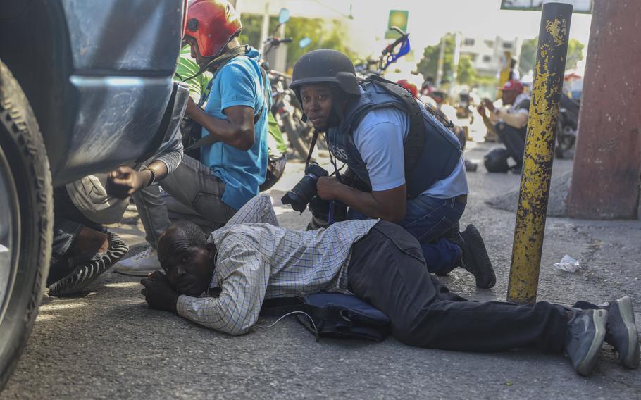 Journalists take cover from the exchange of gunfire between gangs and police