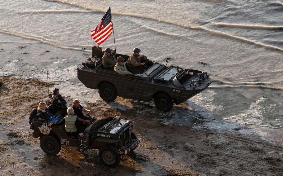 Vintage military vehicles drive along the beach in Normandy, June 6, 2024. 