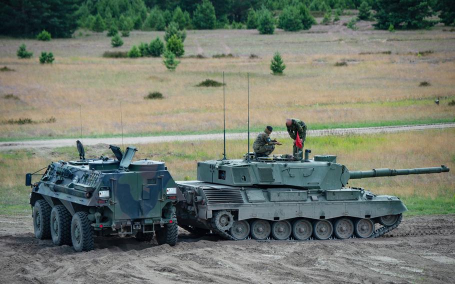 A German trainer instructs a Ukrainian soldier from atop a Leopard 1 tank June 13, 2024, at the Klietz training range. License plates and faces have been blurred in accordance with German military security requirements.
