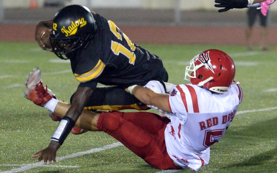 Kadena quarterback DeShaun Nixon gets hauled down by Kinnick defender Nathan DeWolfe, one of three times Nixon was sacked. Nixon ran 41 yards for a second-quarter touchdown.