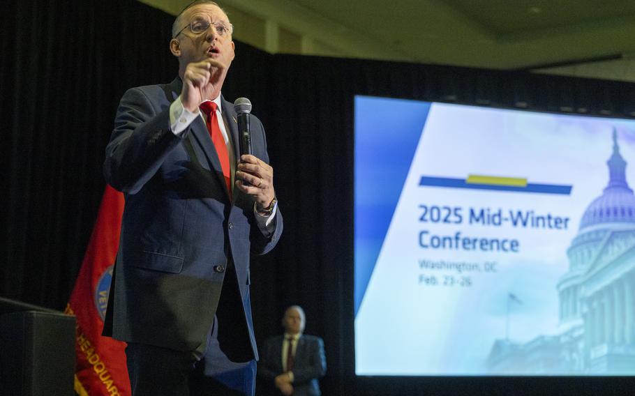 Collins stands with a microphone in his hand addressing the crowd.