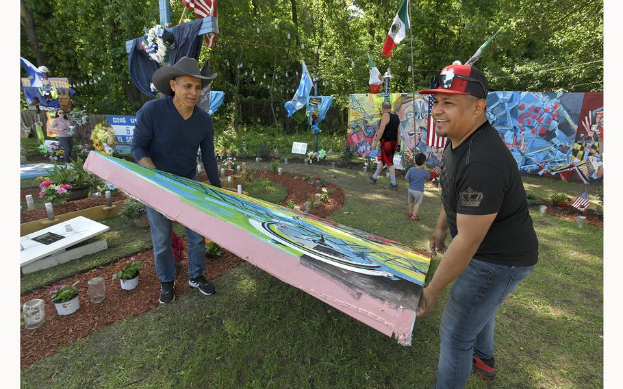 Dallas artist Roberto Marquez, left, and Bernardo Vargas carry to Vargas’s truck. one of the eleven mural panels from the Hawkins Point memorial honoring the six Latino workers who died in the Francis Scott Key Bridge collapse. The city has agreed to store the murals at a city facility until their future home is determined. The crosses and landscaping at the memorial site on Fort Armistead Road will remain for now. 