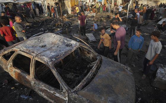 Palestinians look at the damage after an Israeli strike hit a tent area in the courtyard of Al Aqsa Martyrs hospital in Deir al Balah, Gaza Strip, Monday, Oct. 14, 2024. (AP Photo/Abdel Kareem Hana)