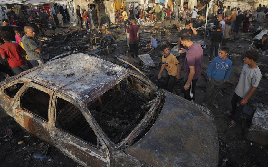 Palestinians look at the damage after an Israeli strike hit a tent area 