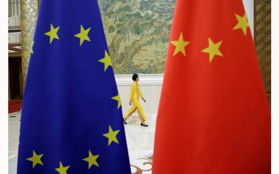 An attendant walks past EU and Chinese flags ahead in Beijing, China, on June 25, 2018. 