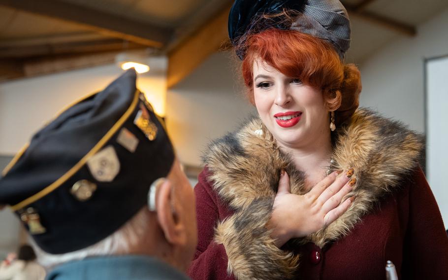 A WWII reenactor dressed as her grandmother places a hand on her heart while speaking to Ceo Bauer.