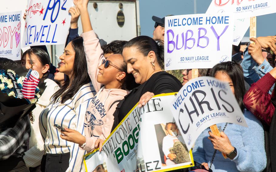 Family and loved ones hold signs during a homecoming ceremony for the USS Stockdale