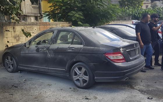 Lebanese security officers stand next of a partly damaged car after what is believed to be the result of a walkie-talkie exploding inside it, in the southern port city of Sidon, Lebanon, Wednesday, Sept. 18, 2024. (AP Photo/Mohammed Zaatari)