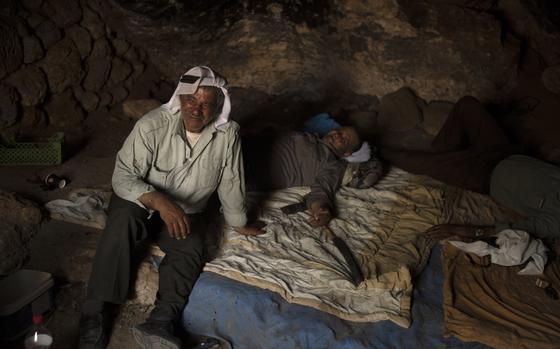 Palestinians Ribhi Ahmad Battat, left, and Issa Ahmad Battat, residents of the West Bank village of Khirbet Zanuta, take shelter from the midday sun in a cave Tuesday, Aug. 27, 2024. Ten months after settlers threatened to kill them if they didn't leave their village, some Palestinian residents are finally home, under a rare court order.