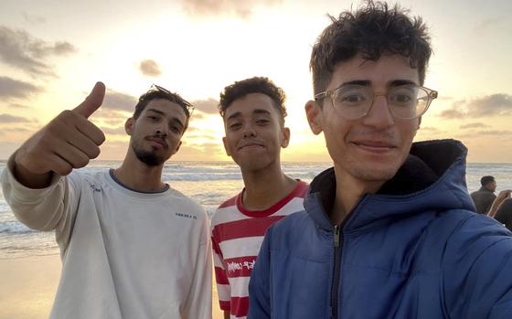 In this undated photo provided by Helmi Hirez, Mohamed (Medo) Halimy, left, and twin brothers Mohammed Hirez, center, and Helmi Hirez, right, stand on a beach in Gaza.   (Helmi Hirez via AP).