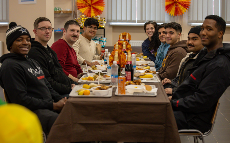 Service members stationed at Camp Kosciuszko, Poland, gather around a table to share a Thanksgiving meal