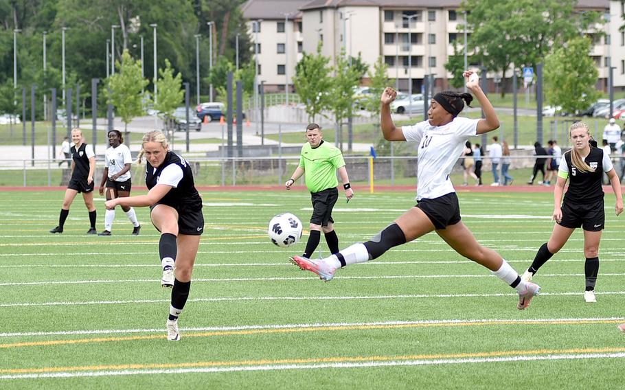 Stuttgart striker Leeba Curlin shoots as Kaiserslautern defender Jedaiah Quinland sticks out a leg to try to block it during a semifinal match at the DODEA Division I European championships May 22, 2024, at Ramstein High School on Ramstein Air Base, Germany.