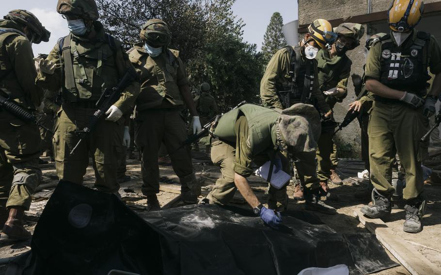 Soldiers recover the bodies of civilians who died during the Hamas attack in Kfar Azza.