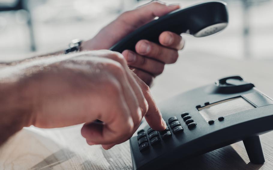 Person dialing number on landline phone in office