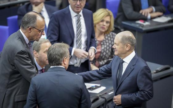 German Chancellor Olaf Scholz, right, and the faction leader of the German Christian Democratic party (CDU), Friedrich Merz, right, shake hands before a questioning during a meeting of the German federal parliament, Bundestag, at the Reichstag building in Berlin, Germany, Wednesday, Dec. 4, 2024. (Kay Nietfeld/dpa via AP)