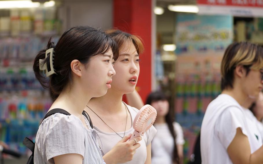 Women use a portable electric fan to combat heat in Tokyo's Shinjuku ward, Wednesday, July 31, 2024.