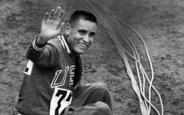 Billy Mills, a U.S. Marine, waves after winning Olympic gold in the 10,000-meter event at the Tokyo Olympics in 1964. Mills won a dramatic, elbow-jabbing, traffic-jam stretch run, beating out Mohammed Gamoudi of Tunesia, who got silver, and world record holder and favorite Ron Clarke of Australia, who captured the bronze.