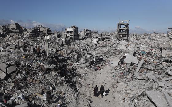 Palestinians walk through the destruction caused by the Israeli air and ground offensive in Jabaliya, a day after the ceasefire deal between Israel and Hamas came into effect, Monday, Jan. 20, 2025. (AP Photo/Abed Hajjar)