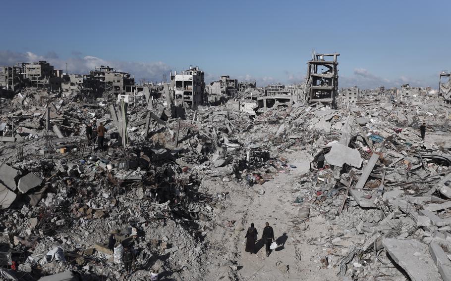 Palestinians walk through destroyed buildings and homes.