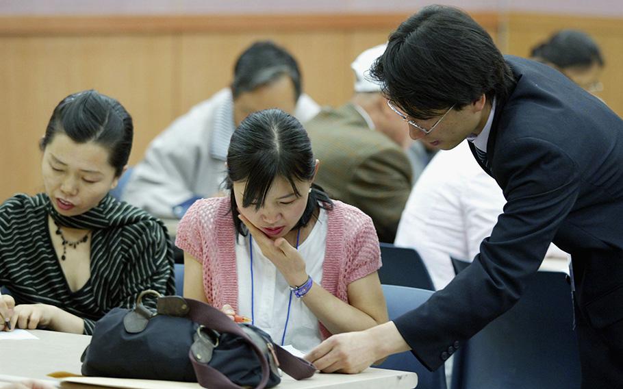 An official from Seoul assists North Korean defectors filling out job applications during an employment lecture on May 10, 2005, in Seoul, South Korea. 