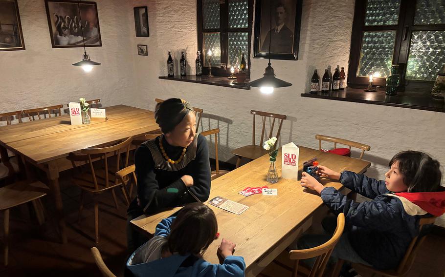 Three people sit around a wooden table