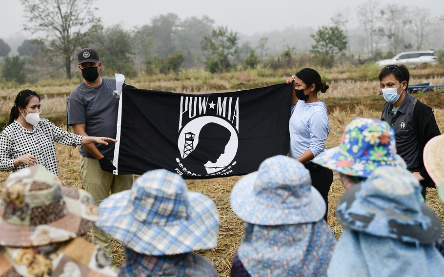 A group of people outdoors, some holding a flag.