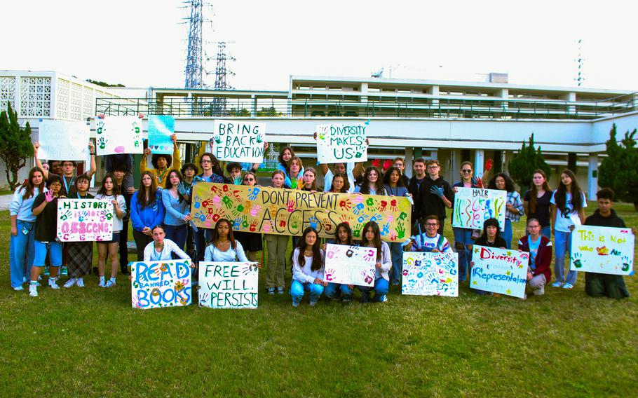 Student protesters hold up signs while posing for a group photo.