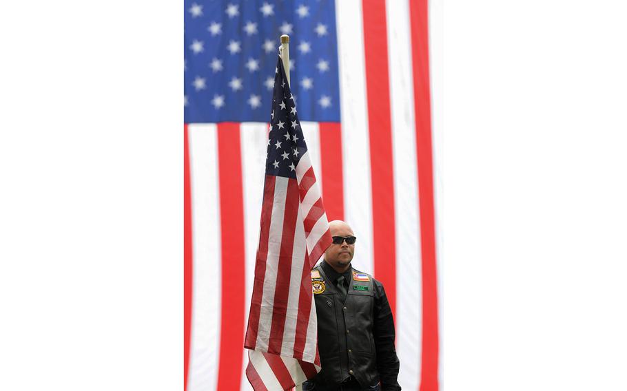 A member of the Patriot Guard Riders stands at attention in front of a giant American flag as four Connecticut veterans, whose unclaimed remains were located and identified by the Missing in America Project, were honored and laid to rest at the State Veterans Cemetery in Middletown.