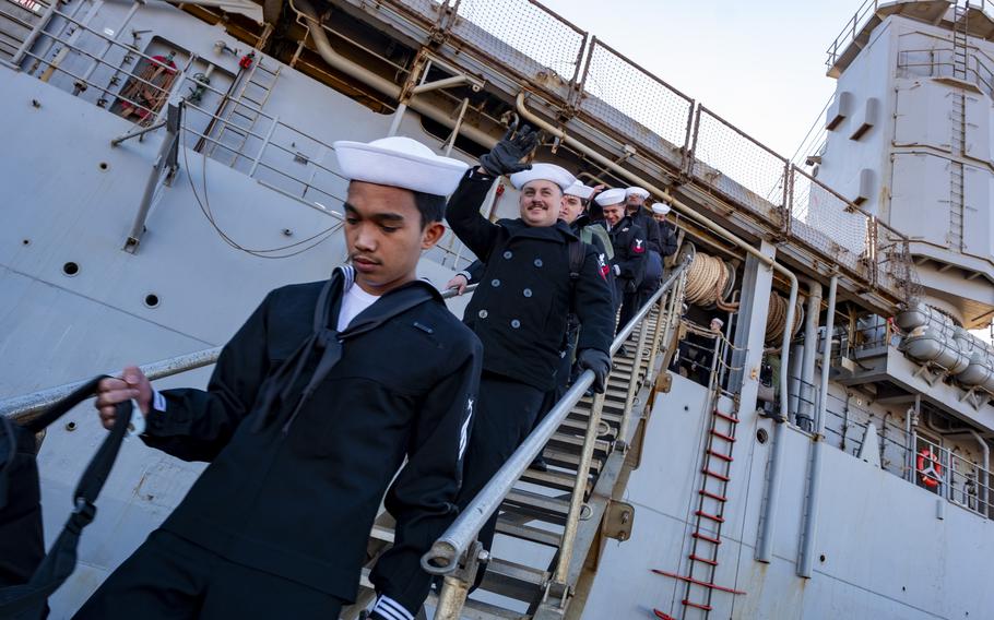 Sailors walk down the stairs from the USS Oak Hill after arriving in port.