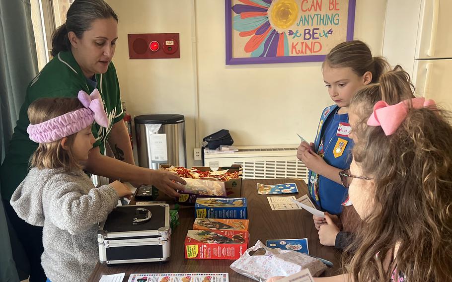 Air Force Maj. Jacelyn Splichal teaches Girl Scouts how to interact with cookie customers Yokota Air Base, Japan, Feb. 4, 2023.