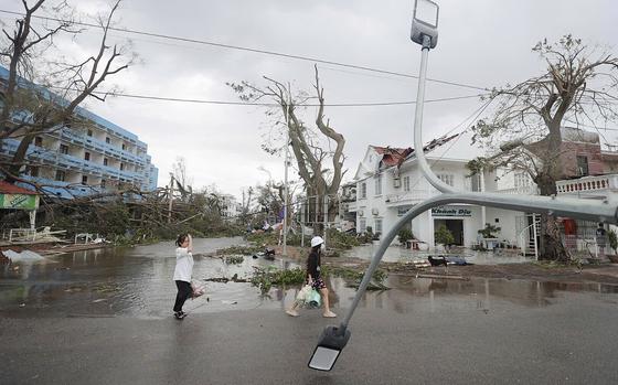 People walk past broken light post after typhoon Yagi hit the city, in Hai Phong, northern Vietnam on Sunday, Sept. 8, 2024. (Minh Quyet/VNA via AP)