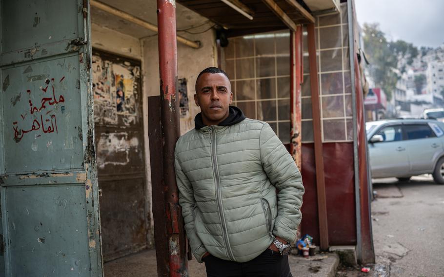 Abdullah Khezaran, 29, stands for a portrait near an entrance to the Balata refugee camp.