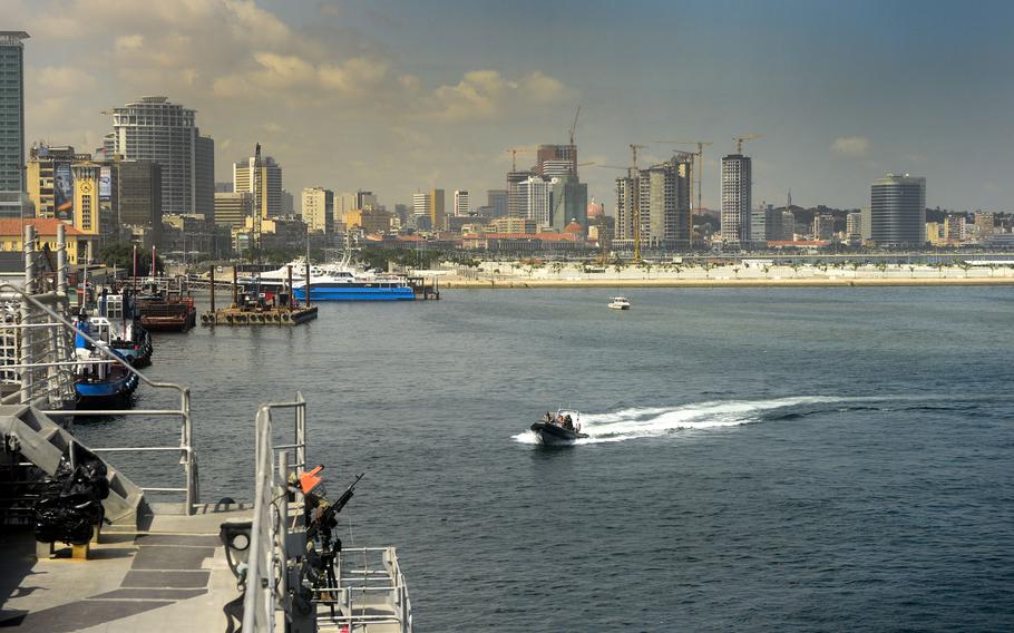 A boat transits a port with a skyline in the background.