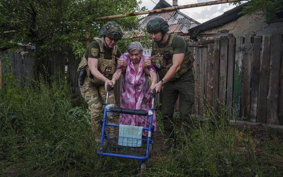 Police officers of the White Angels unit help an elderly woman evacuate to safe areas in Toretsk, Donetsk region, Ukraine, Friday, June 28, 2024. 